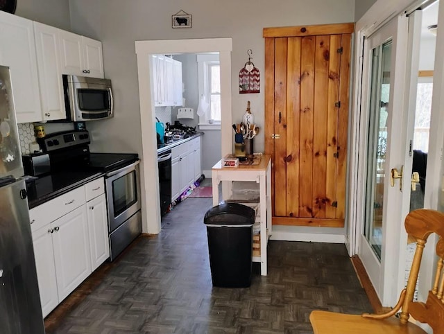 kitchen featuring dark countertops, appliances with stainless steel finishes, white cabinets, and decorative backsplash