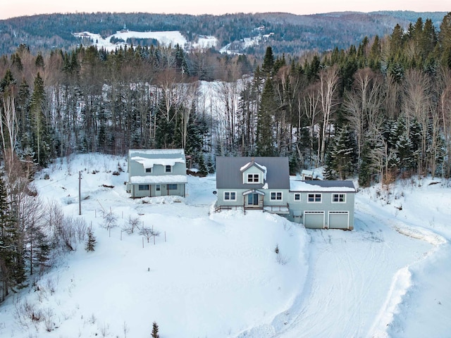 snowy aerial view with a wooded view