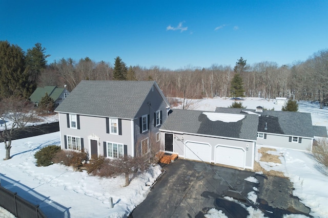 view of front of property featuring driveway, an attached garage, and a wooded view