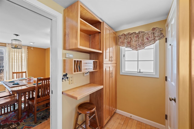 kitchen with light countertops, light wood-style flooring, baseboards, and open shelves