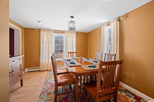 dining area featuring light wood-type flooring, a baseboard radiator, and baseboards