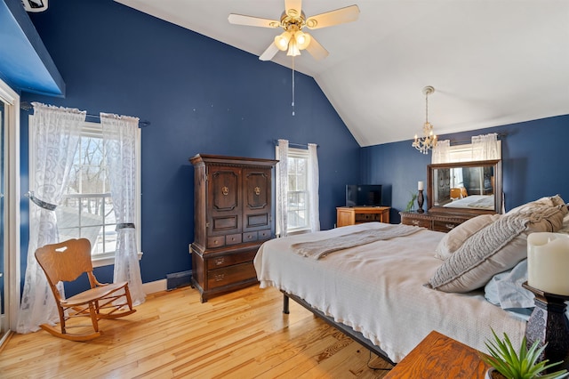 bedroom featuring baseboards, vaulted ceiling, wood finished floors, and ceiling fan with notable chandelier