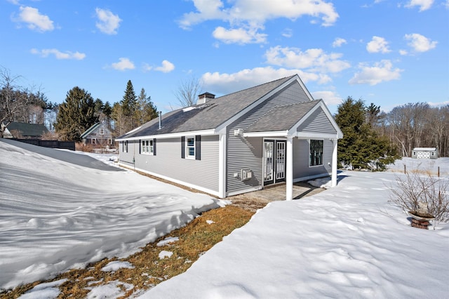 view of snowy exterior with a shingled roof