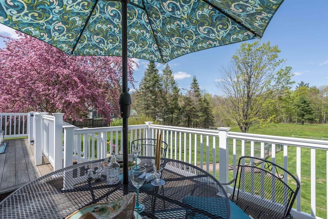 wooden deck featuring outdoor dining space and a lawn