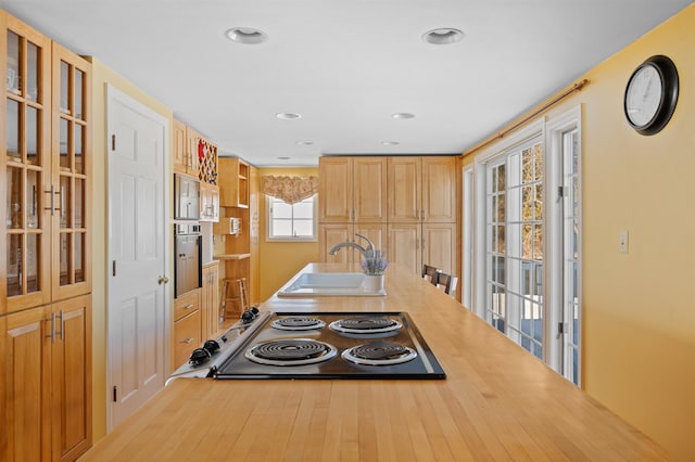 kitchen featuring glass insert cabinets, oven, stovetop, a sink, and recessed lighting