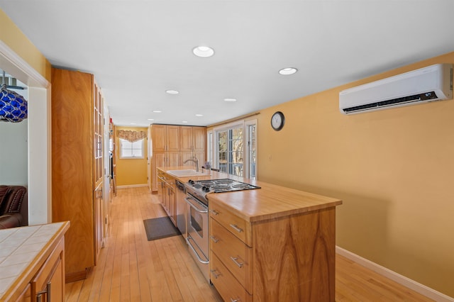 kitchen featuring french doors, light wood finished floors, tile counters, stainless steel range with electric stovetop, and a wall mounted air conditioner