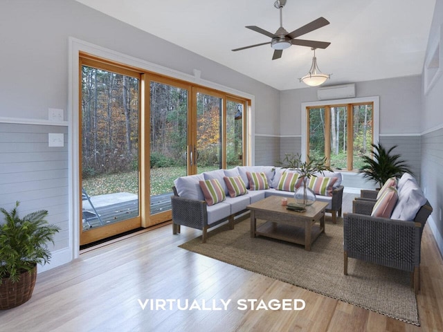 living area with a wainscoted wall, vaulted ceiling, wood finished floors, and an AC wall unit