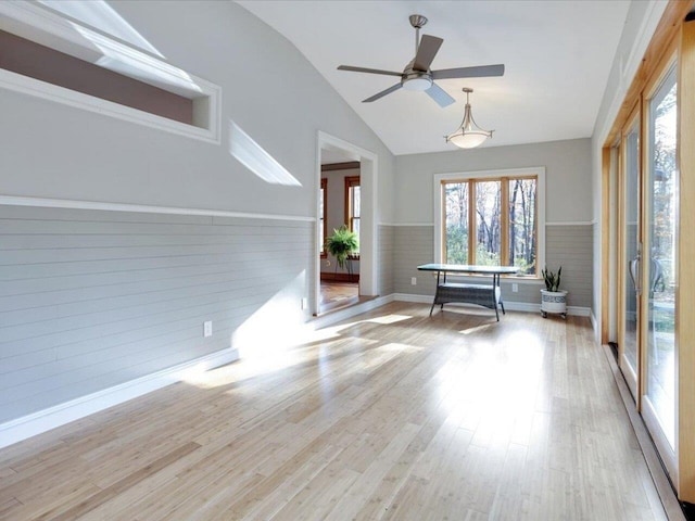 empty room featuring a wainscoted wall, a ceiling fan, vaulted ceiling, and wood finished floors