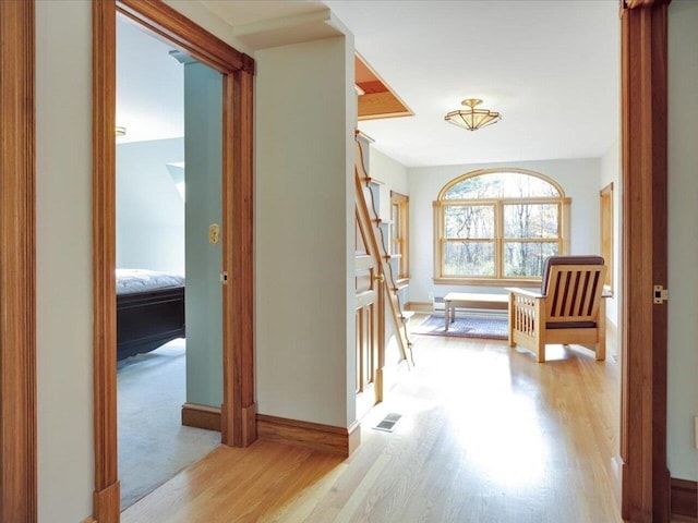 corridor with stairs, wood finished floors, visible vents, and baseboards