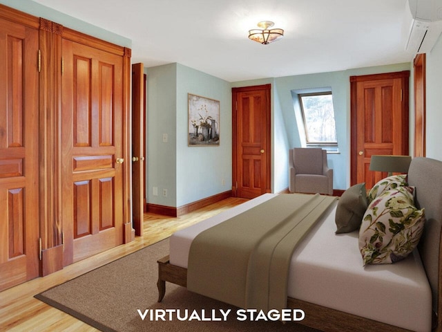 bedroom with light wood-type flooring, an AC wall unit, and baseboards