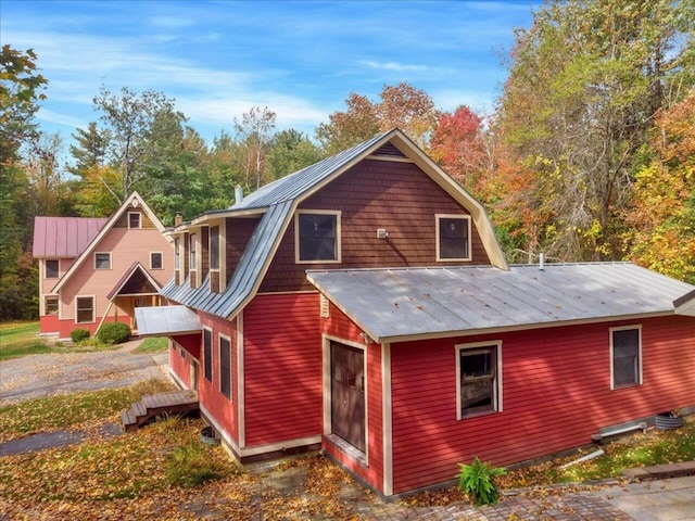 back of property with metal roof, a standing seam roof, and a gambrel roof