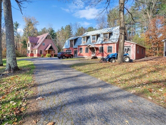 view of front of house featuring metal roof, driveway, a front lawn, and a standing seam roof