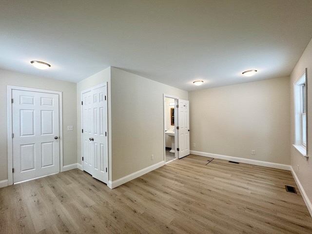 spare room featuring visible vents, baseboards, and wood finished floors