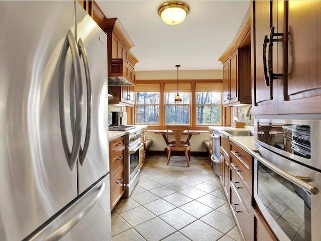 kitchen featuring appliances with stainless steel finishes, light countertops, a sink, and decorative light fixtures