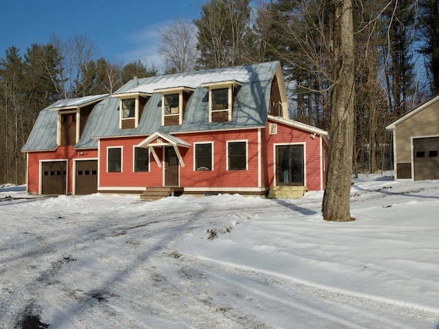 view of front facade with a garage, metal roof, and a gambrel roof