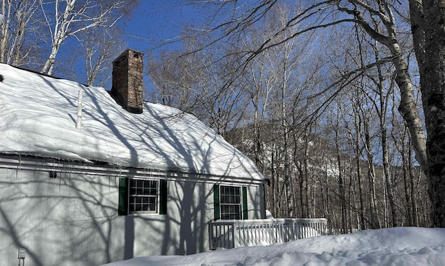 view of snowy exterior with a chimney