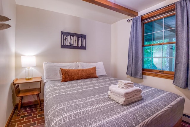 bedroom featuring brick floor, beam ceiling, and baseboards