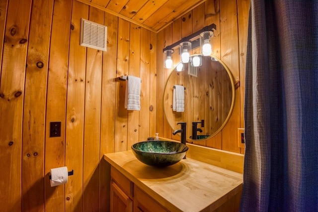 bathroom featuring wood ceiling, wooden walls, and vanity