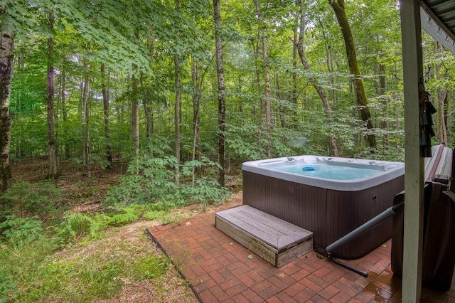 view of patio with a hot tub and a wooded view