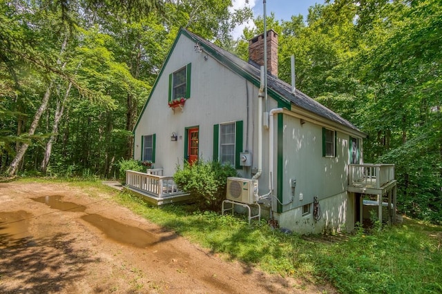 view of property exterior with a deck, ac unit, and a chimney