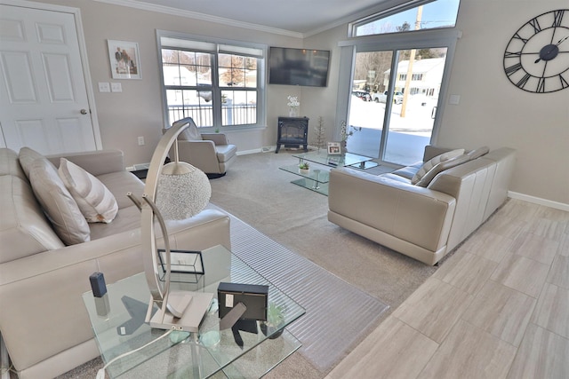 carpeted living room featuring a wood stove, baseboards, ornamental molding, and a wealth of natural light