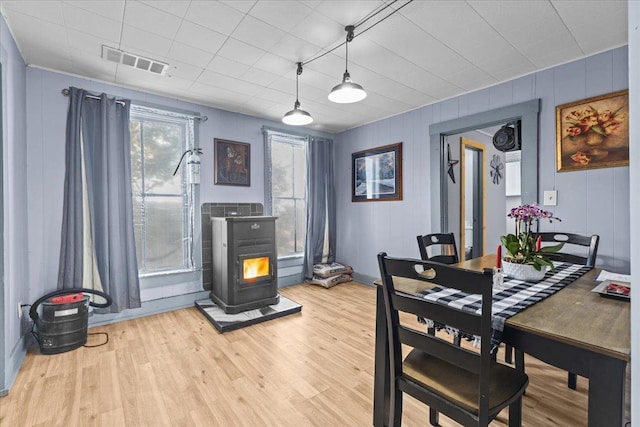 dining area featuring visible vents, light wood finished floors, and a wood stove