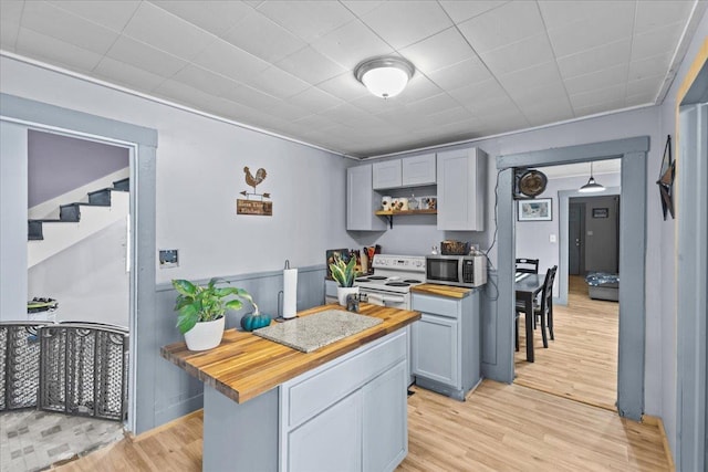 kitchen featuring open shelves, white electric range, stainless steel microwave, wooden counters, and light wood-style floors