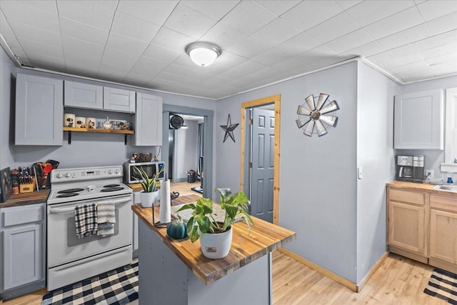 kitchen featuring light wood finished floors, electric range, butcher block countertops, stainless steel microwave, and open shelves