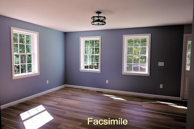 spare room featuring baseboards and dark wood finished floors