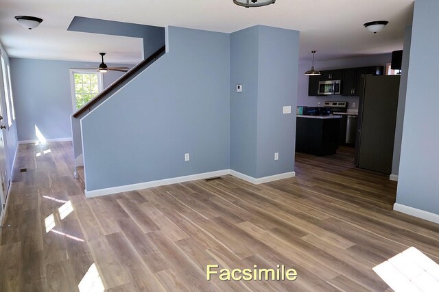 unfurnished living room with wood finished floors, visible vents, baseboards, and stairs