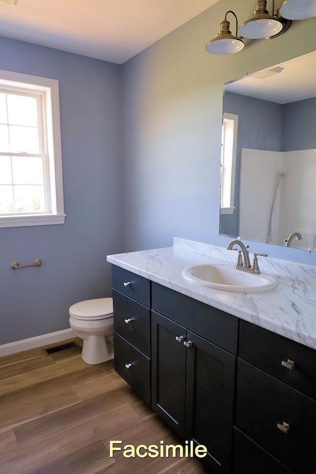 bathroom featuring toilet, wood finished floors, vanity, visible vents, and baseboards