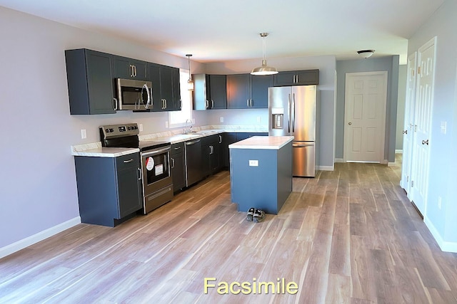 kitchen with light countertops, appliances with stainless steel finishes, a sink, and light wood-style flooring