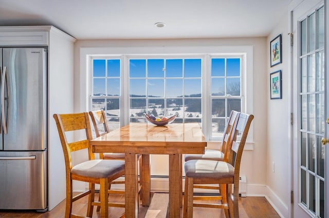 dining area featuring baseboards, wood finished floors, and a healthy amount of sunlight