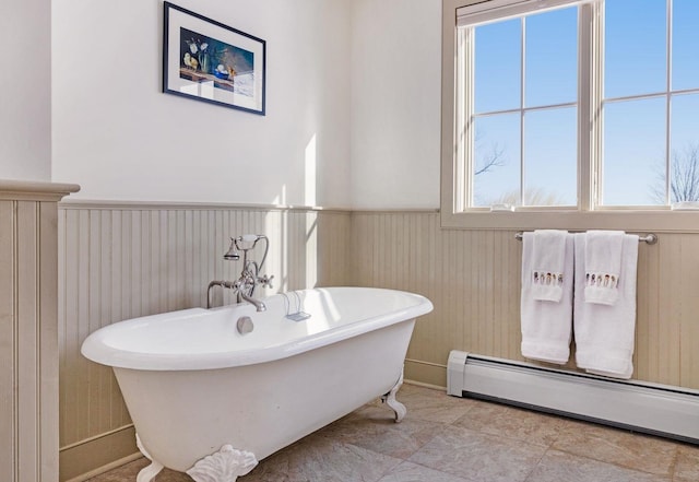 full bathroom featuring wood walls, baseboard heating, a freestanding bath, and wainscoting