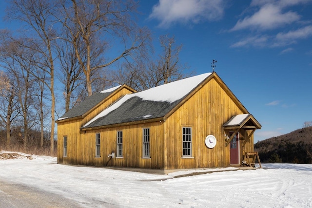 snow covered property with a shingled roof