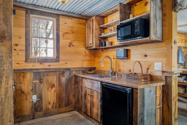 kitchen featuring wooden walls, open shelves, a sink, brown cabinets, and black appliances