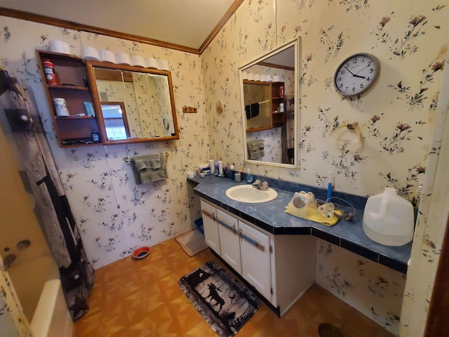 bathroom with wallpapered walls, ornamental molding, vaulted ceiling, and vanity