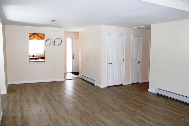 unfurnished room with a baseboard radiator, wood finished floors, and baseboards