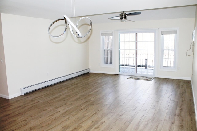 empty room with baseboards, a baseboard heating unit, and wood finished floors