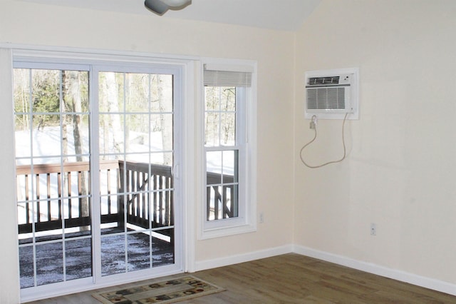 doorway featuring a wall mounted air conditioner, vaulted ceiling, baseboards, and wood finished floors