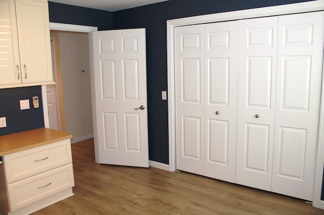 unfurnished bedroom featuring a closet, baseboards, and light wood finished floors