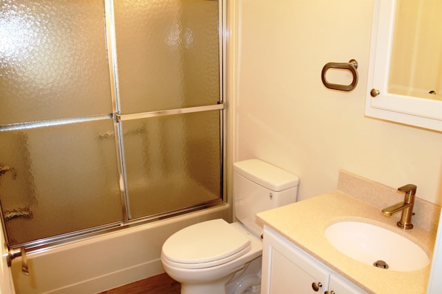 bathroom featuring combined bath / shower with glass door, vanity, and toilet