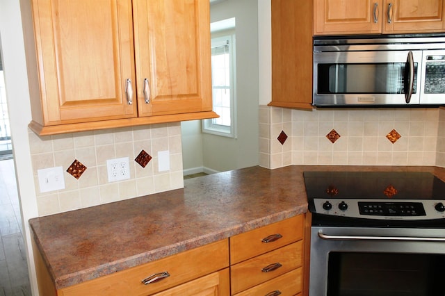 kitchen featuring stainless steel appliances, dark countertops, and backsplash