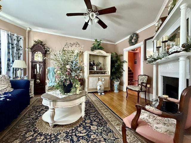 living room with a fireplace, crown molding, stairway, ceiling fan, and wood finished floors