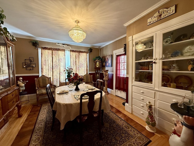 dining area featuring crown molding, a notable chandelier, and wood finished floors