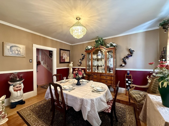 dining room featuring stairs, crown molding, wood finished floors, and an inviting chandelier