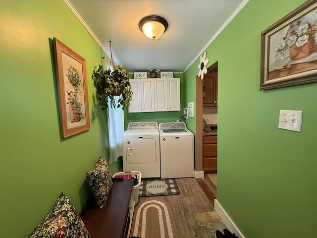 washroom with cabinet space, baseboards, washer and clothes dryer, wood finished floors, and crown molding