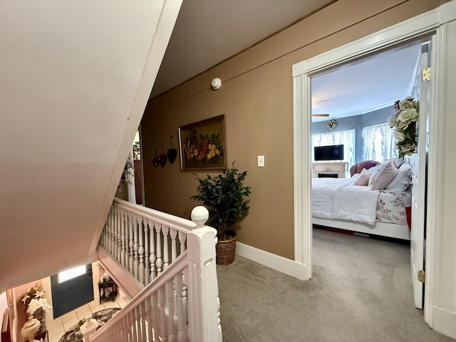 corridor with baseboards, carpet flooring, and an upstairs landing