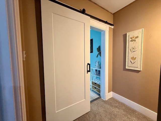 hall featuring carpet floors, a barn door, and baseboards