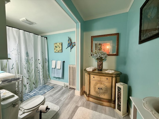 bathroom with radiator heating unit, visible vents, ornamental molding, and wood finished floors